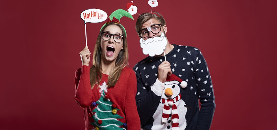 Meisje en jongen met een foute kersttrui en versierd met gekke naambordjes