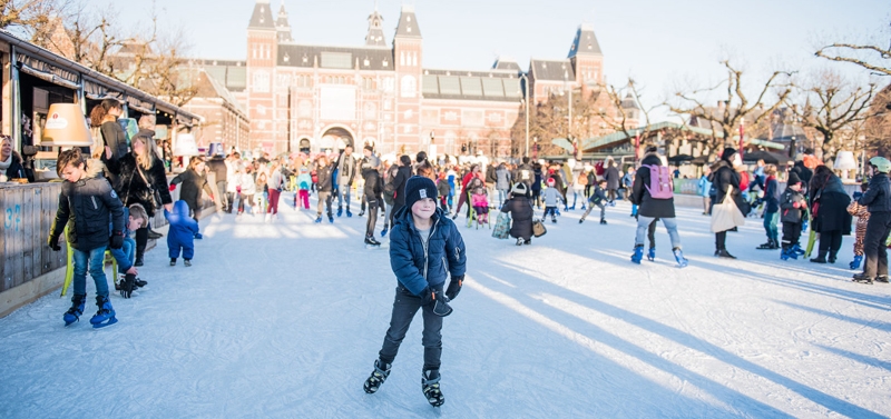 Schaatspret op de schaatsbaan van het museumplein met op de achtgrond het Rijksmuseum